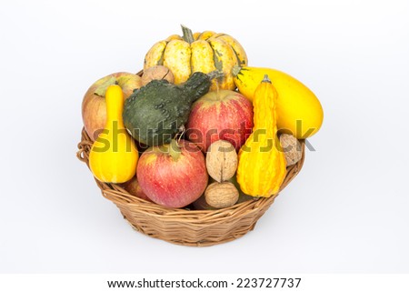 Wicker basket with autumn fruit and vegetables on a white background