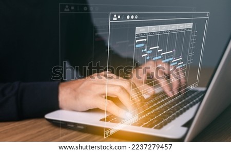 Project manager working on laptop and updating tasks and milestones progress planning with Gantt chart scheduling interface for company on virtual screen.