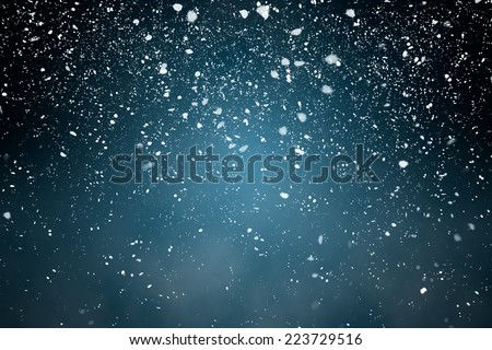 Snowfall with Blue Background - Fluffy snowflakes falling in front of a blue background with vignette