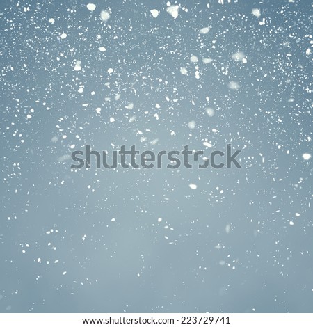 Snowfall with Light Blue Background - Fluffy snowflakes slowly falling in front of a light blue background with vignette
