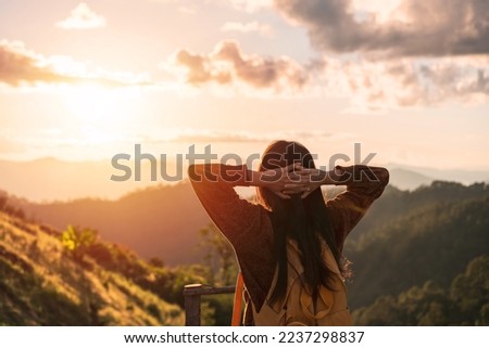 Happy young woman traveler relaxing and looking at the beautiful sunrise on the top of mountains, Travel lifestyle concept Royalty-Free Stock Photo #2237298837