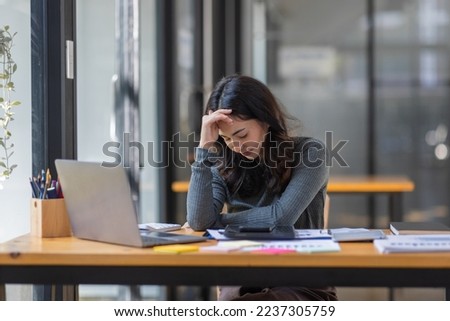Portrait of tired young business Asian woman work with documents tax laptop computer in office. Sad, unhappy, Worried, Depression, or employee life stress concept	 Royalty-Free Stock Photo #2237305759