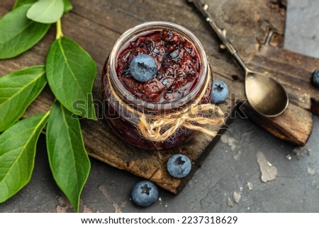 homemade blueberry jam in a jar and fresh blueberries. place for text, top view.