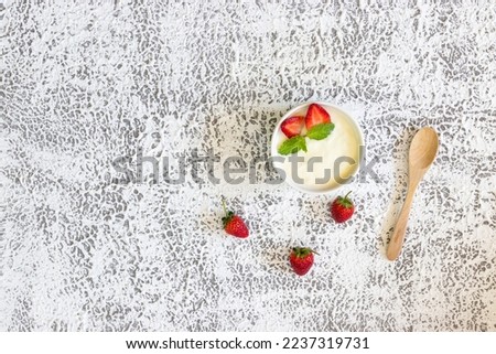 Top view of Strawberry yogurt in a wooden bowl with granola,  mint and fresh strawberry on wooden background. Health food concept.	