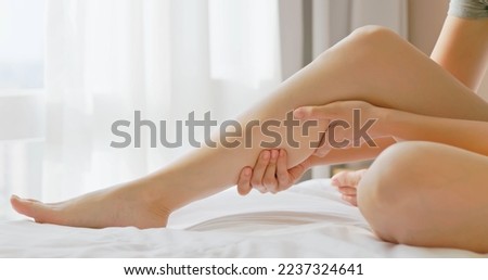 close up of asian woman hand touch massage her calf on bed in bedroom at home - she has leg cramp muscle pain Royalty-Free Stock Photo #2237324641