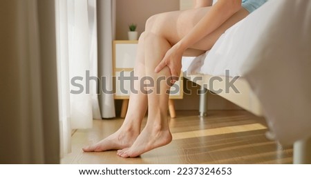 close up of asian woman hand touch massage her calf on floor in bedroom at home - she has leg cramp muscle pain Royalty-Free Stock Photo #2237324653