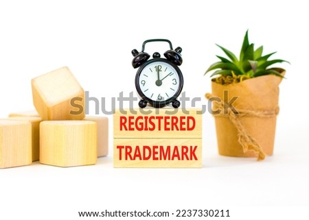 Registered trademark symbol. Concept word Registered trademark wooden blocks. Beautiful white table white background. Black alarm clock. Business and registered trademark concept. Copy space.