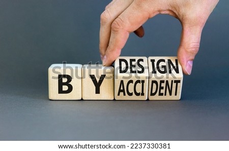 By accident and design symbol. Concept word By accident By design on wooden cubes. Beautiful grey table grey background. Businessman hand. Business by accident and design concept. Copy space.