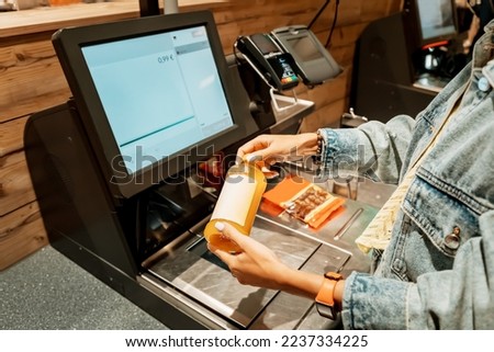 A girl customer scanns and pays for bottle of juice from a supermarket in an automated self-service checkout terminal Royalty-Free Stock Photo #2237334225