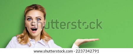 Portrait of very happy, excited surprised, astonished businesswoman with wide opened eyes, mouth, showing copy space text area. Success in business concept. Bright green background.