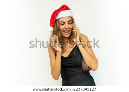 Smiing pretty woman talking by mobyle phone. Wearing black  dress and red santa hat.  New year mood. White background.