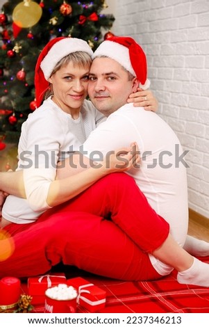 Cheerful couple enjoying winter holidays on weekend vacation. Romantic young couple exchanging Christmas gifts. Young happy attractive amorous couple embracing and kissing. Xmas happiness at home