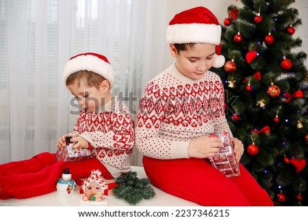 Surprised children unpack Christmas gift boxes. Smiling boys unpacks present. Kids opens Christmas presents. Happiest moment of evening. Holiday for every child. Time to open christmas gifts