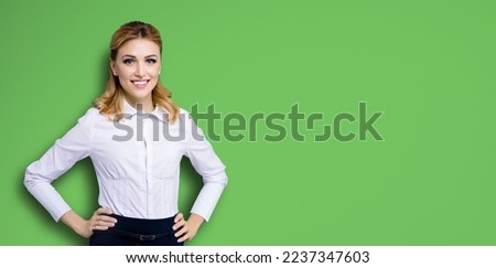 Portrait image of happy smiling businesswoman, with copy space area for text. Confident blond woman in white shirt standing in hands on hips pose, bright green background. Business 