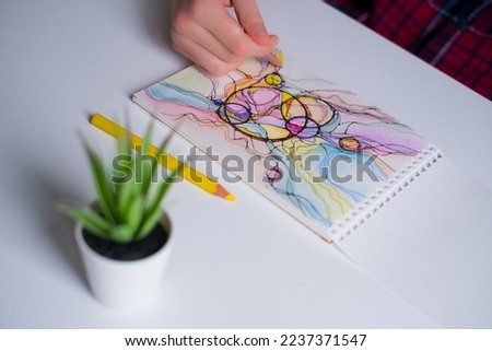Abstract neurographic drawing with colored pencils. Close-up of hands drawing neurographic art. Neurographic Art - a modern method of art therapy