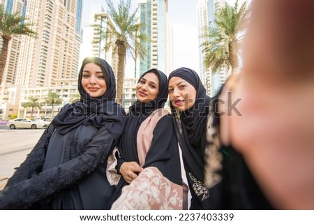 Arab women with abaya bonding and having fun outdoors - Happy middle eastern female friends meeting and talking while shopping