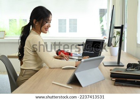 Side view of female freelancer editing video and audio footage with computer software at modern office
