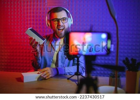 vlogger using smartphone to film podcast in studio. blogger with mobile phone, microphone and headphones filming video for social media broadcasting career Royalty-Free Stock Photo #2237430517