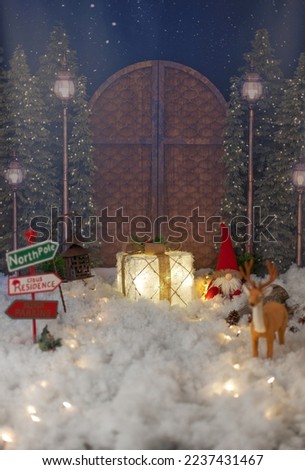 Santa Claus doll sitting in the snow with Christmas surroundings.