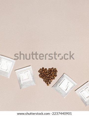 Drip coffee bag and heart from coffee beans, ground coffee for brewing in cup, pack with paper bag drip coffee filter, beige color background, top view, minimal flat lay with copyspace, pastel color