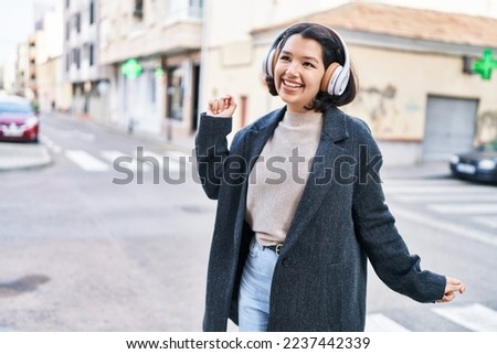 Young woman listening to music and dancing at street