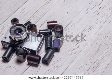 Old retro camera and film reels. On a wooden background.