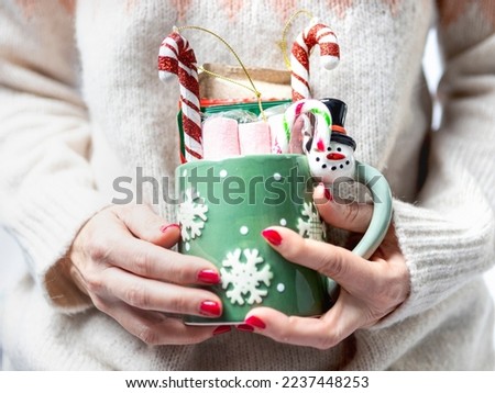 Woman's hands holding a christmas cup with christmas candies