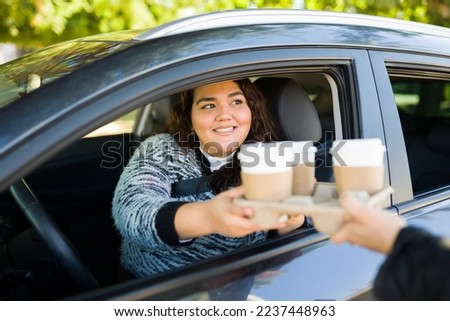 Beautiful latin obese woman driving her car on a through a drive thru buying coffee to go Royalty-Free Stock Photo #2237448963