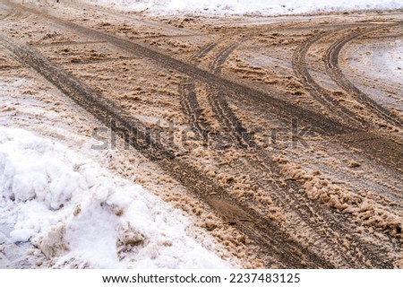 Winter road with crossroad and car tracks in dirty snow and de-icing chemicals.Danger driving in winter.