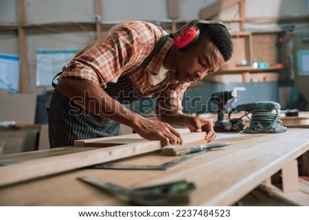 African carpenter measuring wood and timber with electric tools Royalty-Free Stock Photo #2237484523