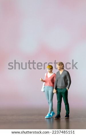 Miniature people man and woman in casual cloth standing together on pink background , Valentine's day concept