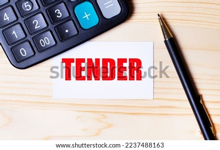 On a light wooden background, a black calculator, a pen and a business card with the text TENDER