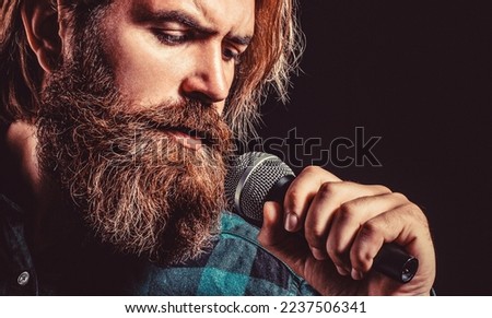 Male singing with a microphones. Bearded man in karaoke sings a song into a microphone.