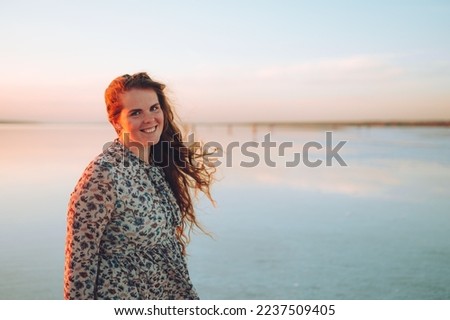 Portrait happy laughing woman in pink dress playful having fun on desert beach of salt pink lake. Ukrainian salt lake