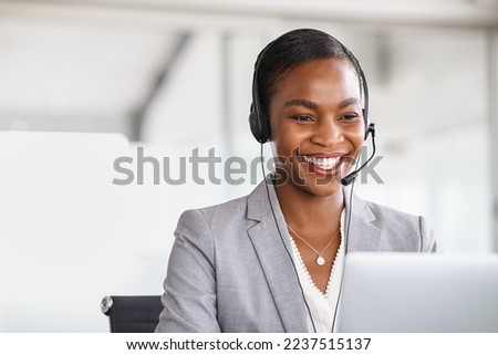 Smiling african american customer care representative working with headset in office. Black woman telemarketing agent working in call center. Call center agent with headset makinga video call. Royalty-Free Stock Photo #2237515137