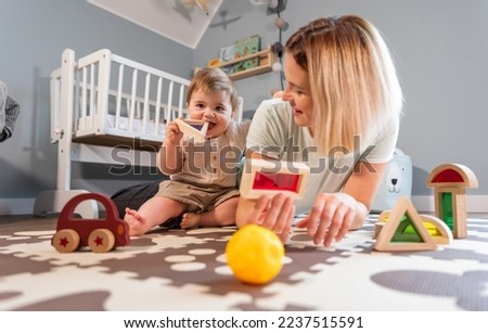 Loving family mom and baby boy playing together toys on floor in child room