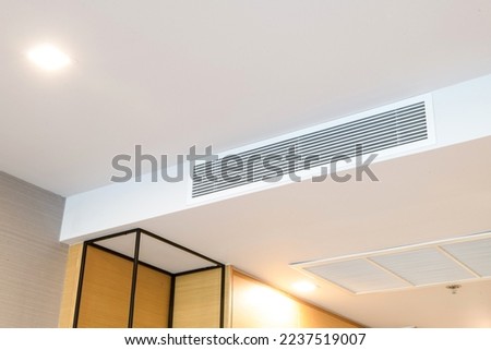 Duct air conditioner for home or office. Ceiling mounted cassette type air conditioner and modern lamp light on white ceiling. Royalty-Free Stock Photo #2237519007