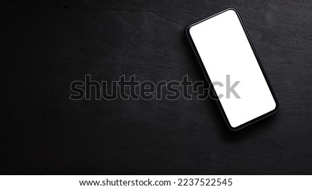 Mock up smart phone on black wooden background. Top view, copy space and blank screen for your advertise design.