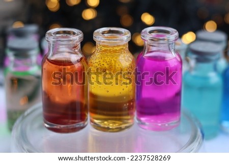 Aqueous solutions of red, yellow and purple indicator dyes are in three glass jars.