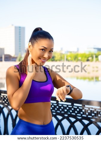 Vertical photo of an asian woman checking her pulse during the race. Concept of modern technologies in sports.