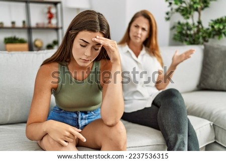 Mother and daughter unhappy arguing sitting on sofa at home Royalty-Free Stock Photo #2237536315