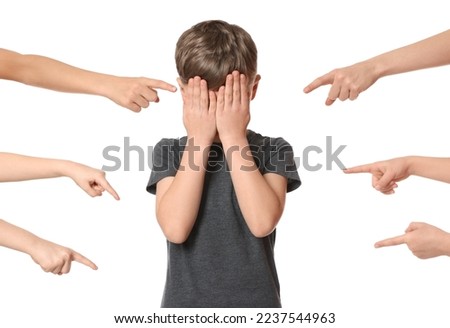 Boy covering face with hands and kids pointing at him on white background. Children's bullying Royalty-Free Stock Photo #2237544963