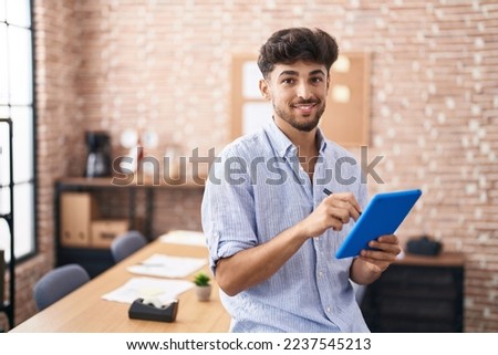 Young arab man business worker writing on touchpad at office
