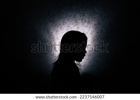 Silhouette of a little girl in the dark. Royalty-Free Stock Photo #2237546007
