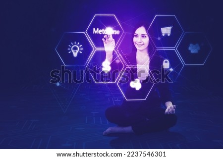 Happy businesswoman touching metaverse word on the virtual screen while sitting in the cyberspace