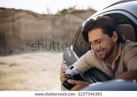 Handsome man travelling by his car and making photos on his camera