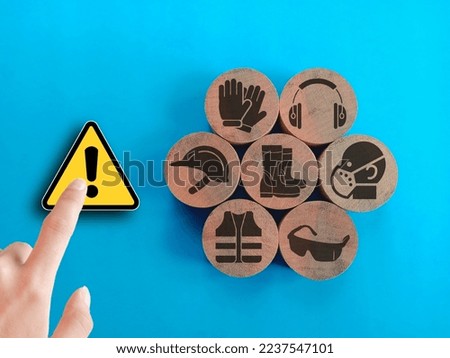 The hand touch at attention symbol and safety icons of workplace safety on wooden blocks isolated blue background .Concept of workplace safety Or Safety at work. Royalty-Free Stock Photo #2237547101