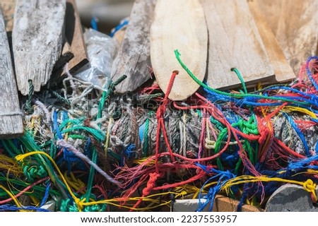 Many suspended chaotically intertwined colorful ropes tied into messy knots for plate wood hanging on rail of traditional. A lot of wooden tags hangs with colorful ropes. Selective focus.