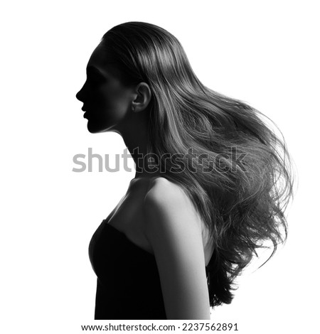 Portrait of a brunette girl with voluminous wavy hair. Black and white image. Side view.