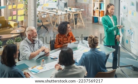 Female Company Operations Manager Holds Meeting Presentation at Office for her Team. Woman Uses a Whiteboard with Company Project Management Plan, Charts, Data. People Work in Creative Office Royalty-Free Stock Photo #2237569217